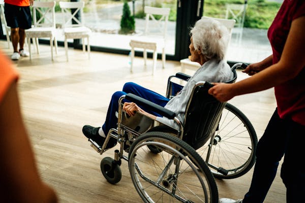 Senior in a wheelchair receiving caregiver assistance